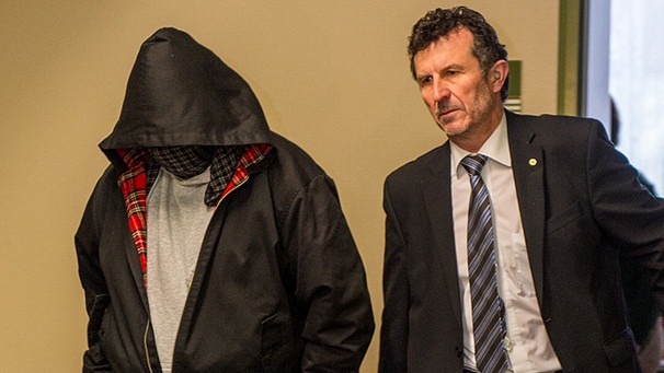 Der V-Mann "Piatto" (links) geht am 3.12.2014 über den Gang des Oberlandesgerichts in München, er hat eine Kapuze tief über das Gesicht gezogen | Bild: picture-alliance/dpa Der V-Mann "Piatto" (links) geht am 3.12.2014 über den Gang des Oberlandesgerichts in München, er hat eine Kapuze tief über das Gesicht gezogen | Bild: picture-alliance/dpa